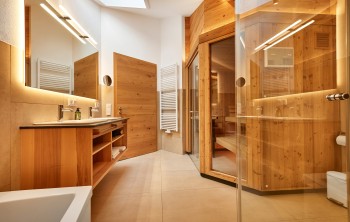 Modernes Bad mit eigener Sauna und hochwertigen Naturmaterialien für entspannte Urlaubsmomente.