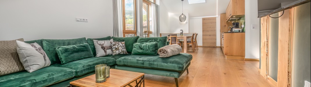 Ankommen und wohlfühlen – großzügiger Wohnbereich mit viel Holz, warmem Design und offener Küche für entspannte Urlaubstage im Schmuckstück.