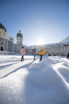 Vor der imposanten Kulisse des Klosters Ettal setzen Winterwanderer ihre Etappe fort.