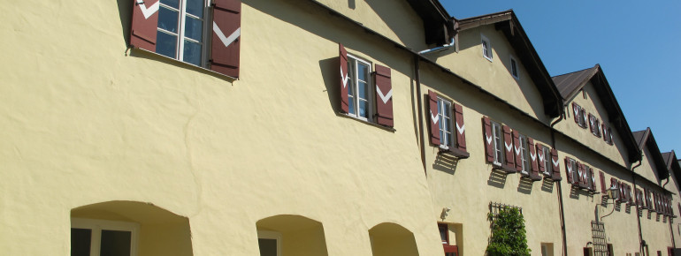 Die Salinenhäuser mit ihren roten Fensterläden stehen am Karl-Theodor-Platz in Traunstein.