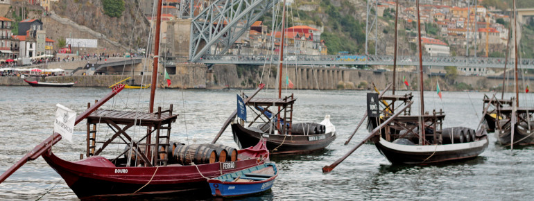 Am Douro-Ufer in Vila Nova de Gaia sieht man Boote mit Portwein-Fässern.