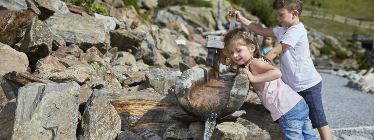 Kinder spielen am Wasserlauf.