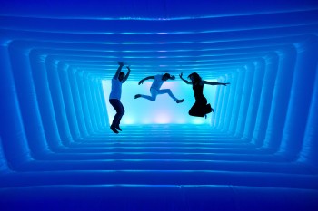 Leuchtende Linien und schwebende Silhouetten lassen den Raum wie einen endlosen Tunnel wirken.