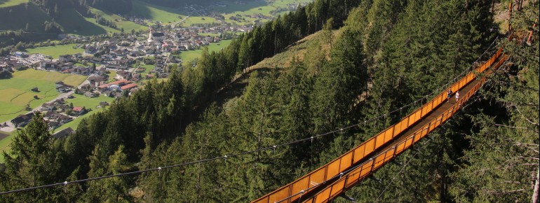 Die Hängebrück am Sunnenseit'n Weg mit dem Blick über Neustift im Stubaital.