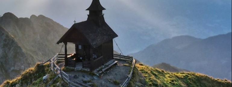 Die ersten Sonnenstrahlen brechen durch die Wolken und tauchen die Kapelle in ein magisches Licht.