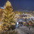 Blick vom Rathaus auf die verschneiten Buden des Klagenfurter Weihnachtsmarktes. Die große Tanne ist mit Lichterketten und Christbaumkugeln geschmückt.