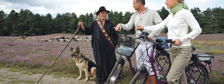 Schäferin mit Schäferhund und Pärchen auf Radtour