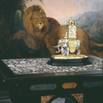 Figurenuhr in Gestalt eines Elefanten Augsburg, Anfang 17. Jahrhundert auf einem Tisch mit Scagliola-Einlagen, München, um 1620/30 Hintergrund: Gemälde mit der Darstellung eines Löwen, Johann Melchior