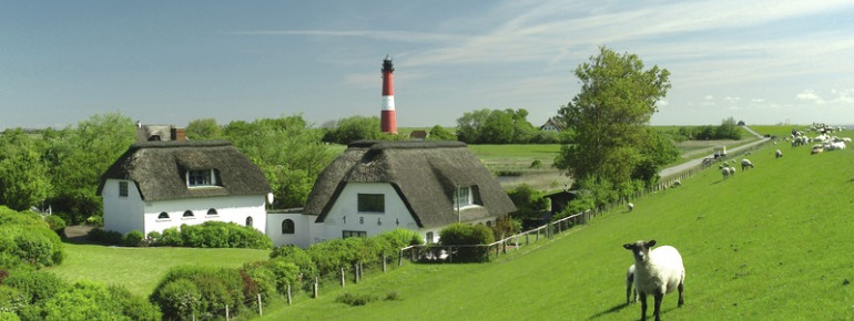 Der rote Turm mit weißem Band steht an der Südseite der Marschinsel Pellworm, hinter dem Seedeich.