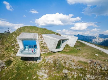 Drei große Fensterfronten durchbrechen die Bergflanke und rahmen gezielte Panoramen auf die Dolomiten, den Ortler und die Zillertaler Alpen.