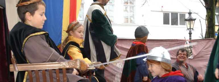 Königlich Geburtstag feiern können junge Besucher auf dem Weihnachtsmarkt in Siegburg. Hier wird das mittelalterlich gekleidete Kind gerade mit einem Ritterschlag geadelt.