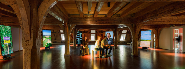 Im Obergeschoss befindet sich eine Medieninstallation mit acht, kreisförmig angeordneten Bildschirmen.