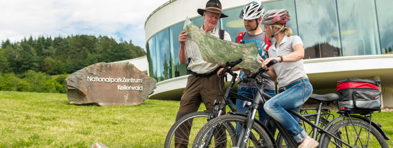 Radfahrer mit einem Ranger vor dem Nationalparkzentrum.