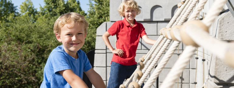 Kleine Ritter erklimmen die Burg über Kletternetze.