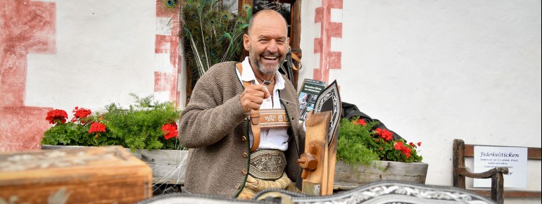 Handwerker demonstrieren vor Ort historische Techniken wie Federkielstickerei.