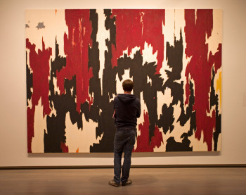 A man standing in front of a painting at the Clyfford Still Museum in Denver.