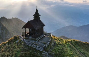 The first rays of sunlight break through the clouds, bathing the chapel in a magical light.