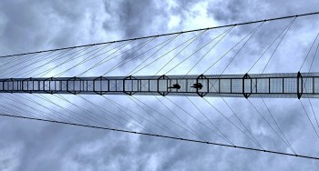 The floor is made of an open metal grid, meaning the drop below is visible straight down at all times.