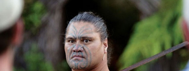 Maori guard standing at the entrance of the village