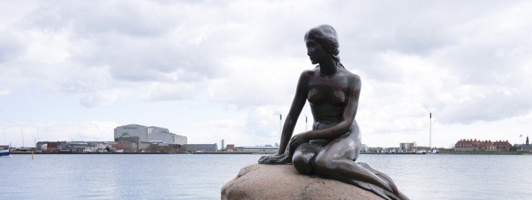 The Little Mermaid in front of Copenhagen&#39;s port scenery