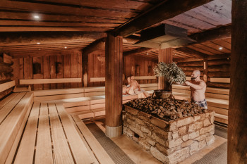 In the rustic Sudhaus infusion sauna, aromatic scents rise from a heavy cauldron.