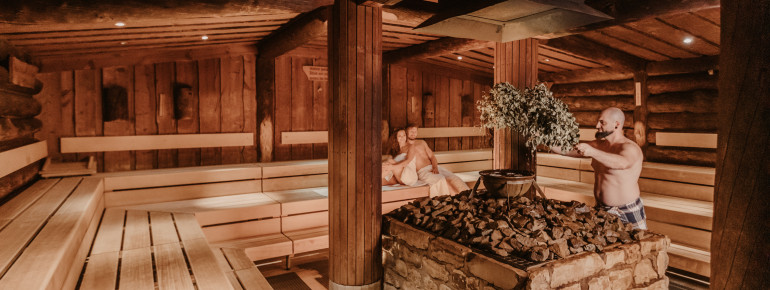 In the rustic Sudhaus infusion sauna, aromatic scents rise from a heavy cauldron.