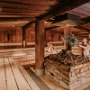 In the rustic Sudhaus infusion sauna, aromatic scents rise from a heavy cauldron.