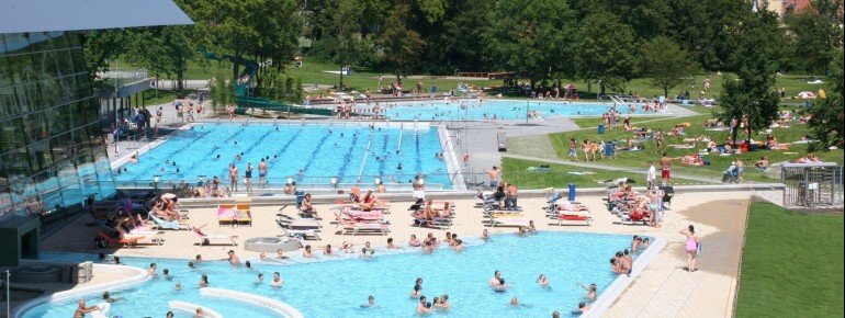 Blick auf den Außenbereich der Bodensee-Therme Konstanz. Hier erwarten dich unter anderem ein Sportbecken, ein Strömungskanal und ein Nichtschwimmerbecken.
