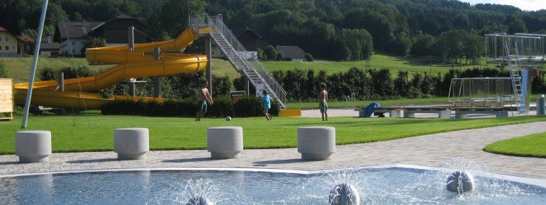 Das Kinderbecken (im Vordergrund) und die große Wasserrutsche (im Hintergrund) im Freibad Thalgau.