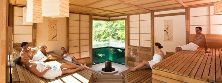 Gesundes Schwitzen in der Meditations-Sauna mit Blick auf echte Koi-Fische.
