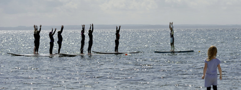 Stand-Up-Paddle Yoga am Strand von Pelzerhaken
