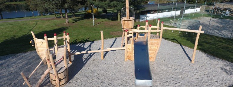 Blick auf den Spielplatz am Stausee Rabenstein. Im Hintergrund sind der Beachsoccer-Platz und die Sanitäranlagen zu sehen.